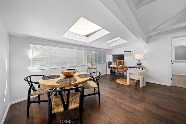 dining room featuring lofted ceiling with skylight, an AC wall unit, dark wood-type flooring, and baseboards