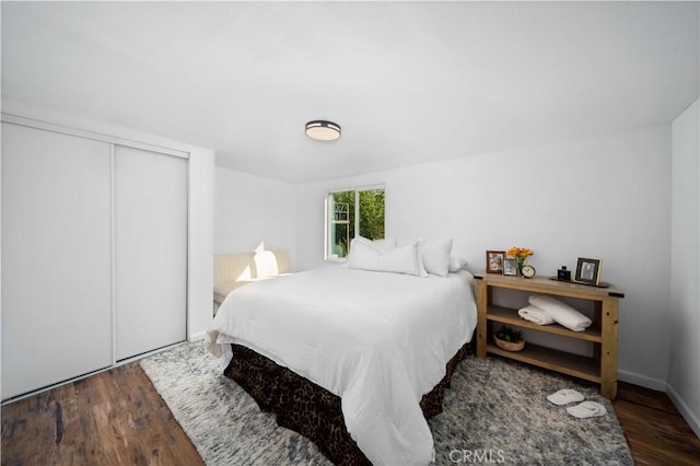 bedroom with a closet, dark wood finished floors, and baseboards