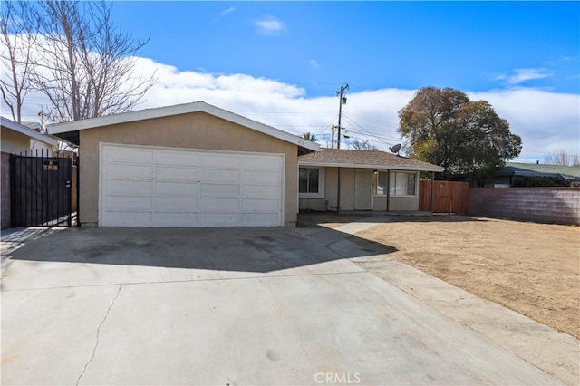 ranch-style house featuring a garage, concrete driveway, fence, and stucco siding