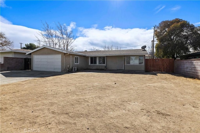 ranch-style house featuring central AC unit, a garage, fence, driveway, and stucco siding