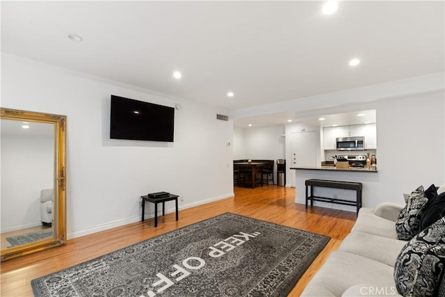 living area with baseboards, light wood finished floors, and recessed lighting