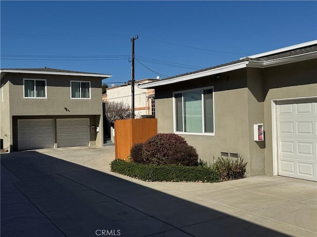 view of home's exterior with a garage, fence, and stucco siding