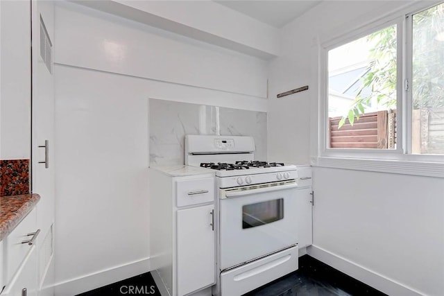 kitchen with white range with gas stovetop, light countertops, baseboards, and white cabinetry