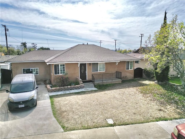 view of front of property featuring a shingled roof, covered porch, fence, and stucco siding