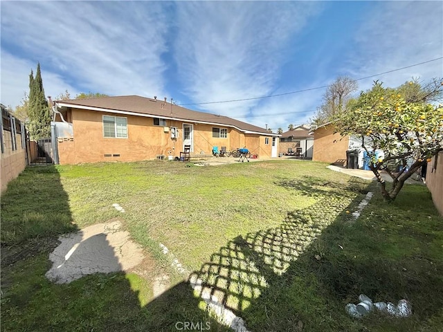 rear view of property with a yard, fence, and stucco siding