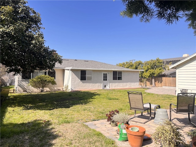 rear view of property featuring stucco siding, a patio area, a lawn, and fence