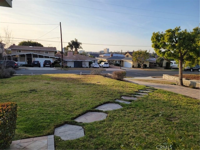 yard at dusk featuring a residential view