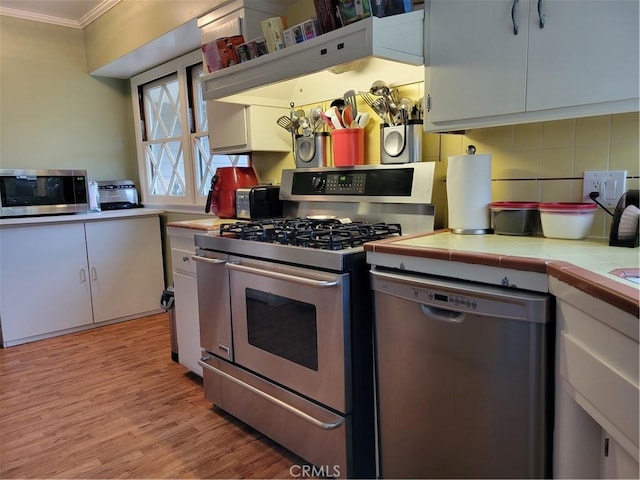 kitchen with stainless steel appliances, tile counters, and white cabinetry