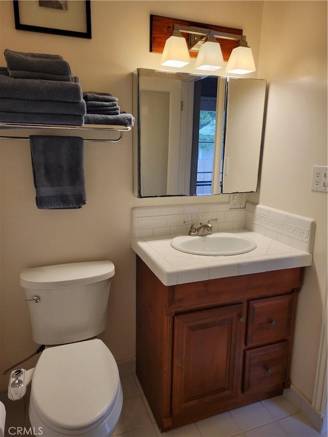 half bathroom featuring toilet, tile patterned floors, baseboards, and vanity