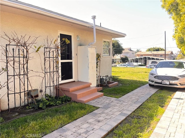 entrance to property featuring a yard and stucco siding