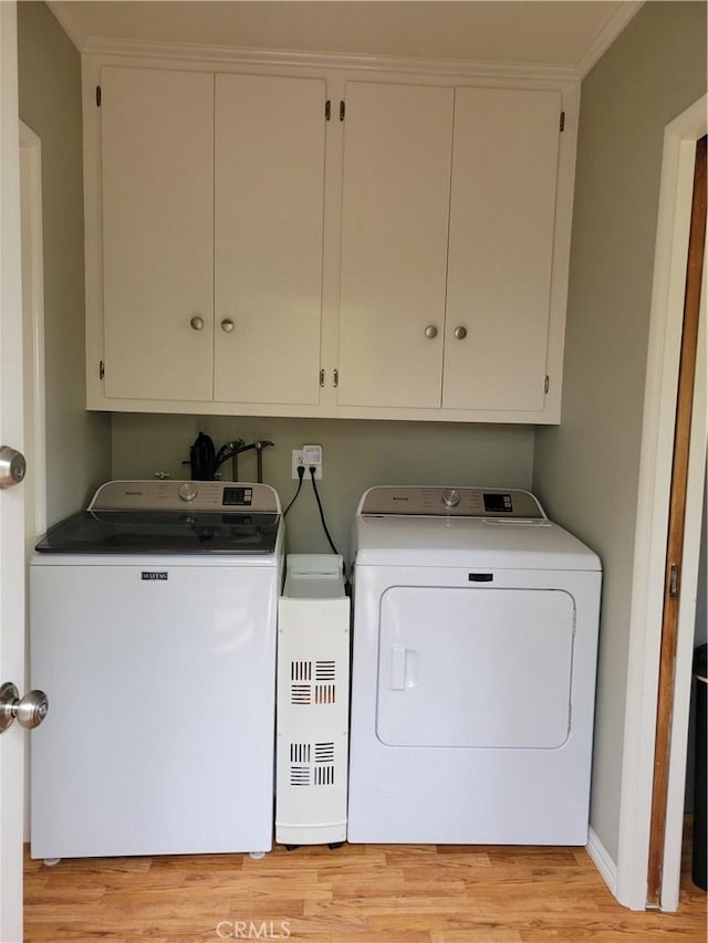 washroom featuring washer and clothes dryer, cabinet space, and light wood-style floors