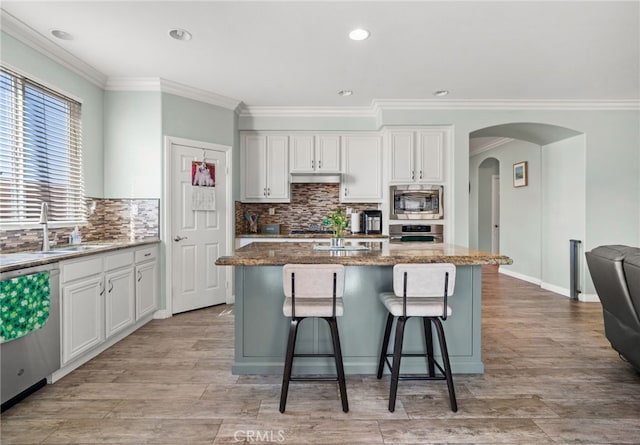 kitchen featuring stainless steel appliances, stone counters, a kitchen island, and white cabinetry