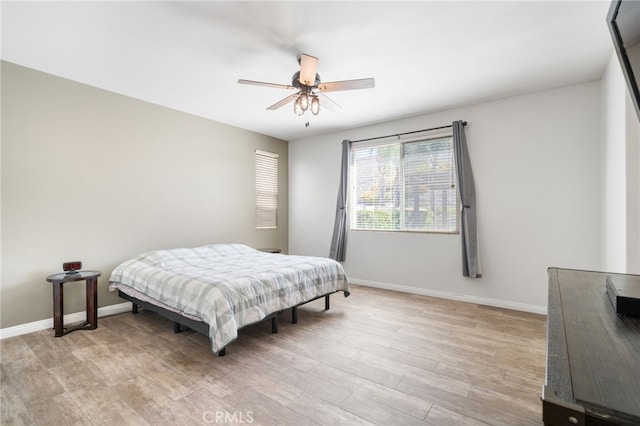 bedroom featuring baseboards, ceiling fan, and light wood-style floors