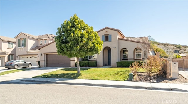 view of front of house with a tile roof, stucco siding, a front yard, fence, and driveway