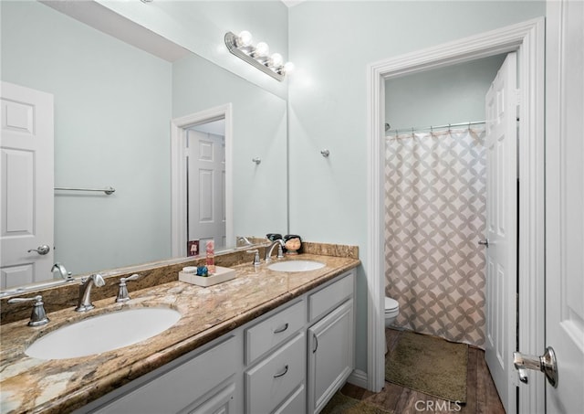 full bath featuring double vanity, curtained shower, a sink, and toilet