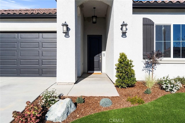 property entrance with a garage, a tile roof, and stucco siding