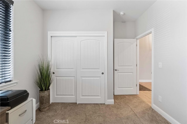 unfurnished bedroom featuring light carpet, a closet, and baseboards