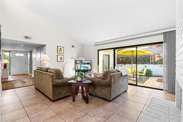 living area with high vaulted ceiling, visible vents, and light tile patterned flooring