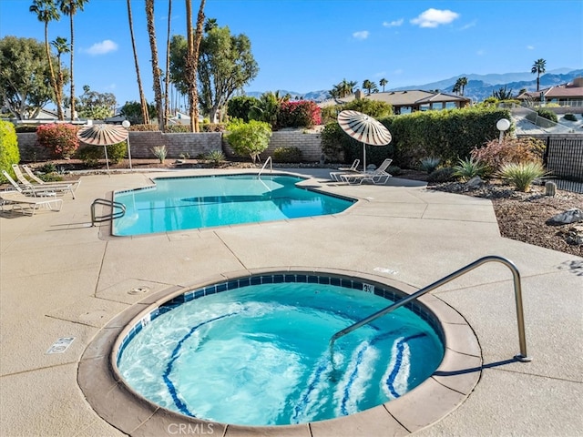 pool with a community hot tub, a fenced backyard, a patio, and a mountain view