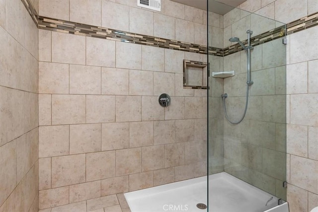 bathroom featuring visible vents and a tile shower