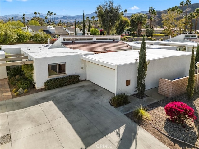 exterior space featuring a garage, driveway, a mountain view, and stucco siding