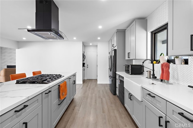 kitchen featuring a sink, decorative backsplash, black appliances, light wood finished floors, and island exhaust hood