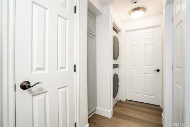 washroom with light wood-type flooring, stacked washing maching and dryer, and laundry area