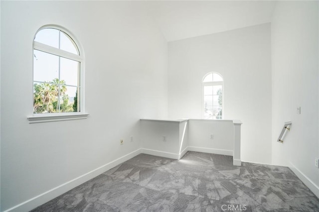 unfurnished room featuring lofted ceiling, baseboards, and carpet flooring