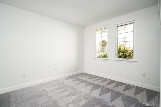 empty room featuring baseboards and light colored carpet