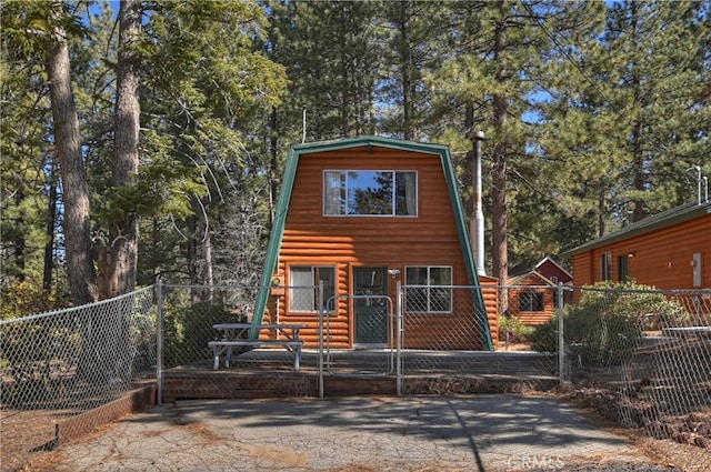 a-frame home with fence and a gambrel roof