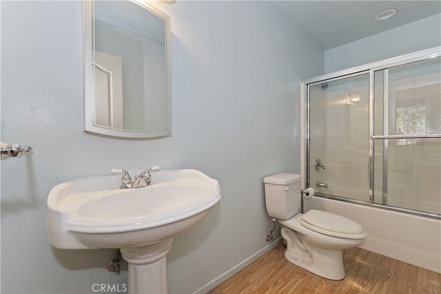 full bath featuring baseboards, enclosed tub / shower combo, toilet, and wood finished floors