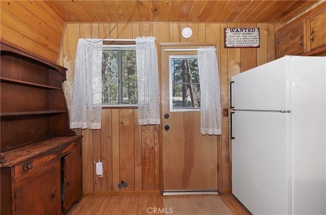 doorway featuring wood ceiling, wood walls, and light wood-style flooring