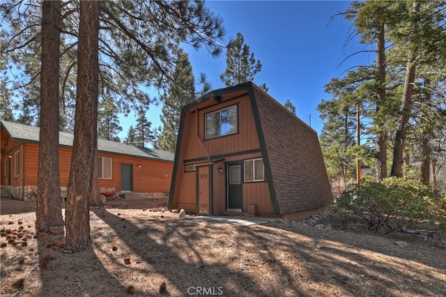 rear view of property with roof with shingles and a gambrel roof