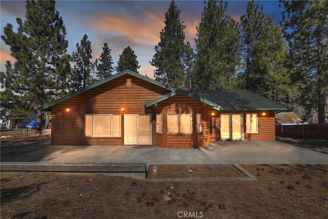 rustic home with a patio area, fence, and faux log siding