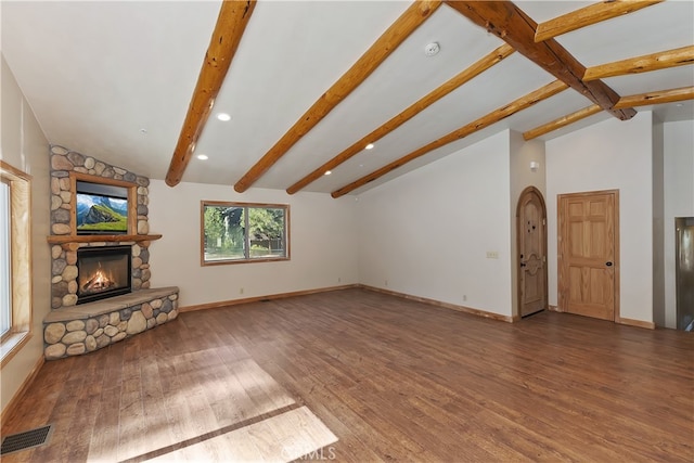 unfurnished living room featuring a fireplace, visible vents, lofted ceiling with beams, wood finished floors, and baseboards