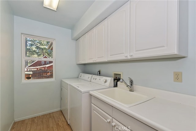 laundry room with light wood-style flooring, a sink, baseboards, independent washer and dryer, and cabinet space