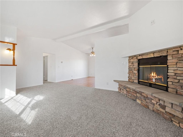 unfurnished living room with carpet, ceiling fan, a stone fireplace, and lofted ceiling with beams