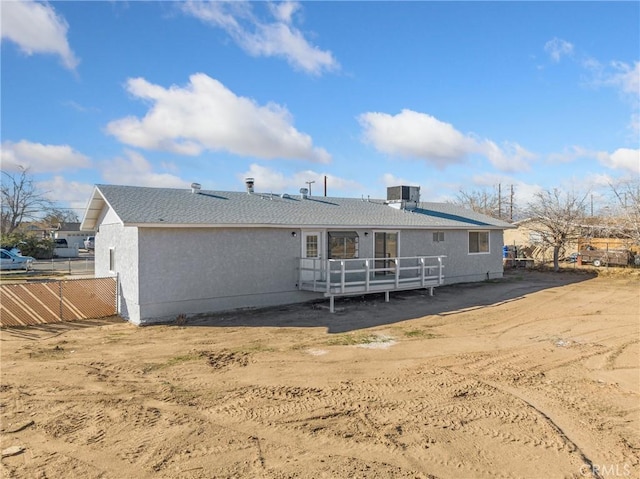 back of house featuring central AC, fence, and stucco siding