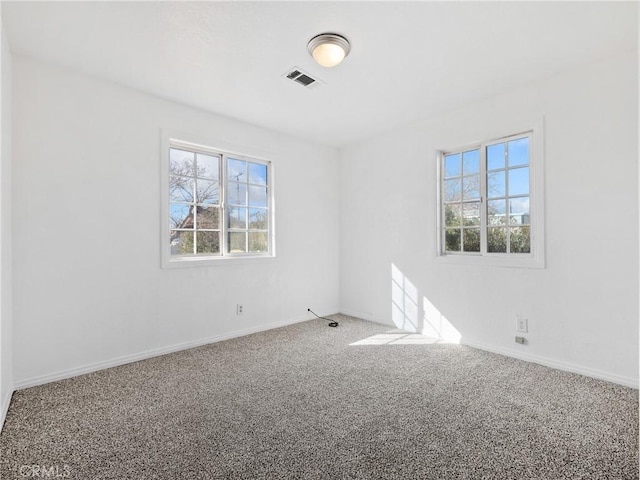 carpeted spare room with visible vents and baseboards