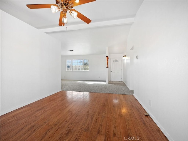 unfurnished living room featuring a ceiling fan, lofted ceiling with beams, baseboards, and wood finished floors