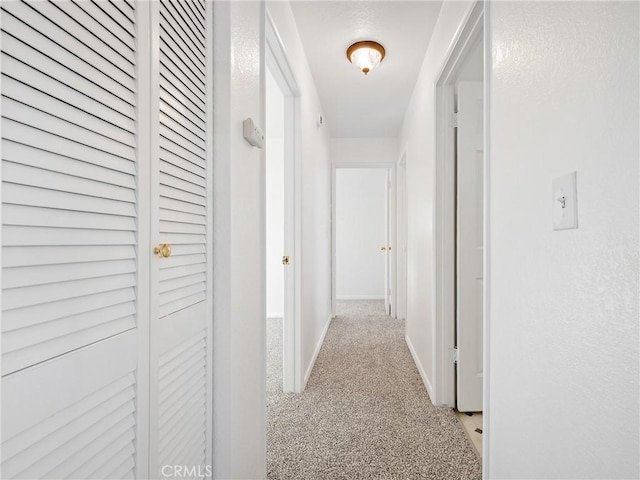 corridor with light carpet and baseboards