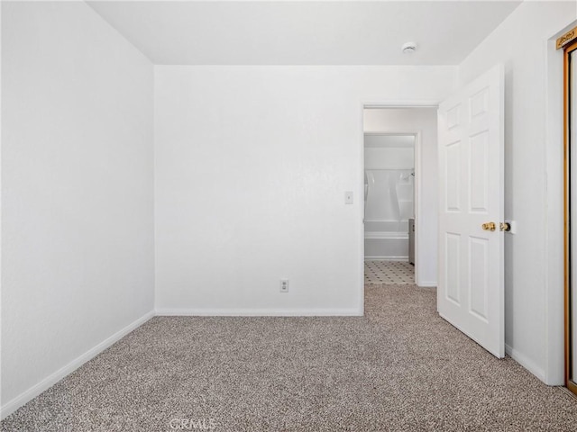 spare room featuring carpet floors and baseboards