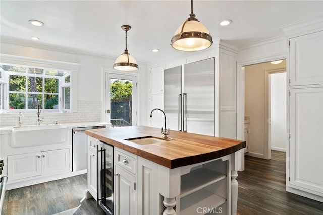 kitchen featuring an island with sink, butcher block countertops, appliances with stainless steel finishes, white cabinetry, and a sink