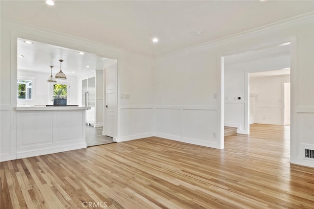 unfurnished room with a decorative wall, recessed lighting, visible vents, light wood finished floors, and crown molding