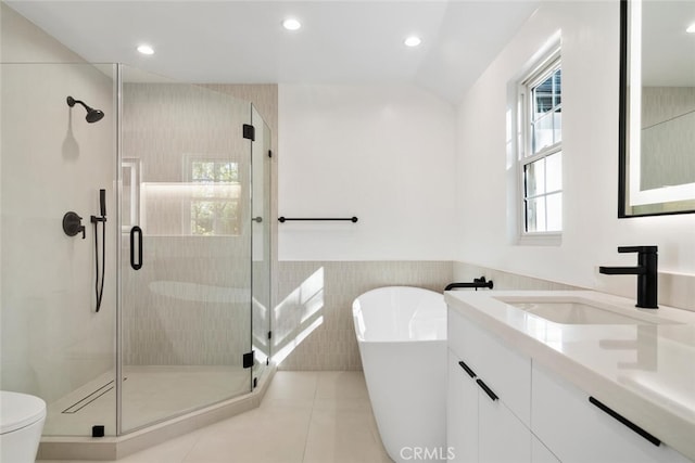 bathroom with tile walls, a freestanding tub, vanity, and a shower stall