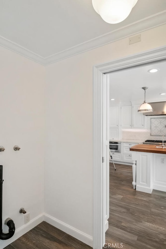 laundry room featuring dark wood-style floors, crown molding, a sink, laundry area, and baseboards