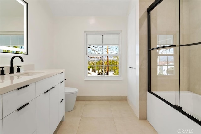 bathroom with tile patterned flooring, toilet, vanity, baseboards, and combined bath / shower with glass door