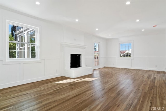 unfurnished living room with a brick fireplace, dark wood-style floors, a decorative wall, and recessed lighting