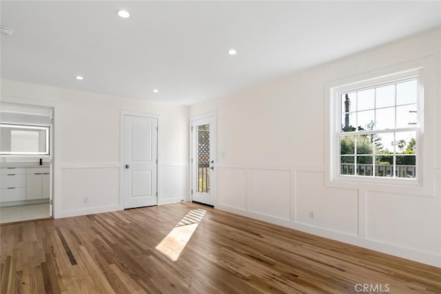 unfurnished room with wainscoting, a decorative wall, wood finished floors, and recessed lighting