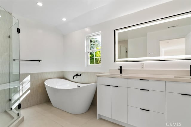 full bathroom featuring a soaking tub, a wainscoted wall, vaulted ceiling, vanity, and recessed lighting